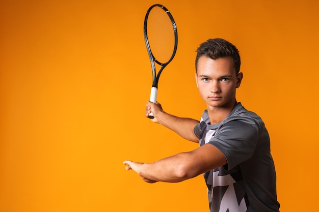 Retrato de un joven tenista sobre fondo naranja