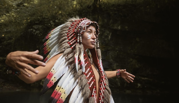 Foto retrato de una joven con tocados nativos americanos contra el fondo de la naturaleza