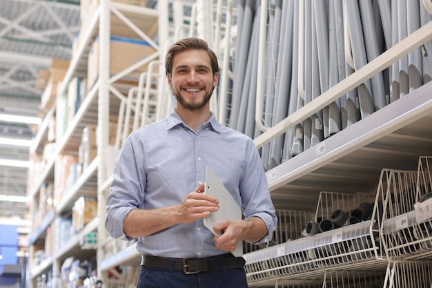 Retrato de un joven trabajador de almacén sonriente que trabaja en una tienda mayorista de efectivo y transporte.