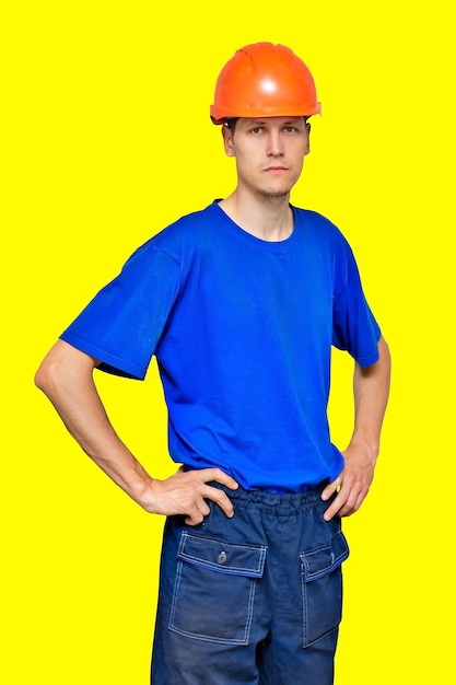 Retrato de un joven trabajador delgado con un casco de construcción y una camiseta azul Un constructor o contratista