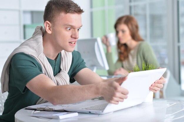 retrato, de, un, joven, trabajando, en, oficina, con, un, computador portatil