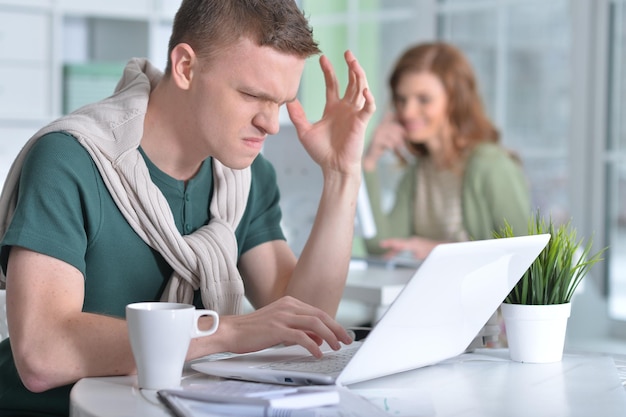 retrato, de, un, joven, trabajando, en, oficina, con, un, computador portatil