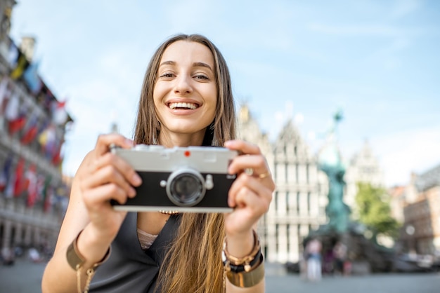 Retrato de una joven turista con cámara de fotos en la gran plaza del mercado en la ciudad de Amberes en Bélgica