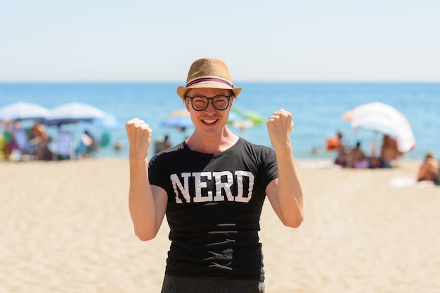 Retrato de joven turista guapo como nerd en la playa en España