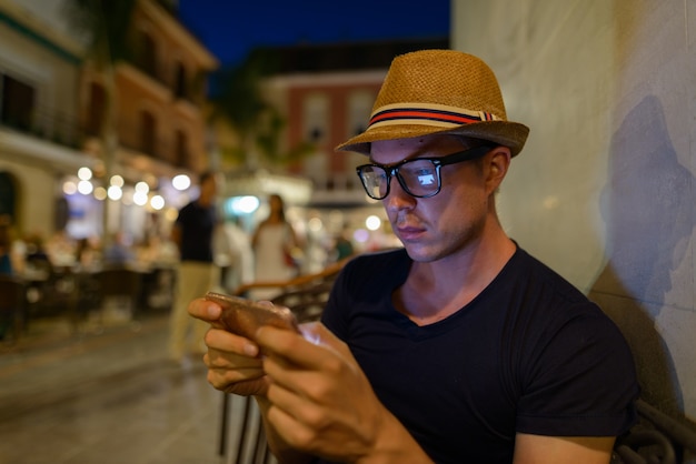 Retrato de joven turista guapo sentado en el restaurante al aire libre