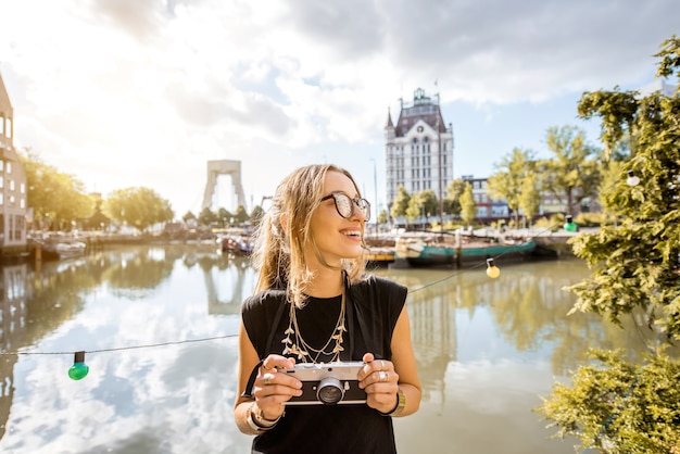 Retrato de una joven turista con photocamera de pie en el puerto viejo de la ciudad de Rotterdam