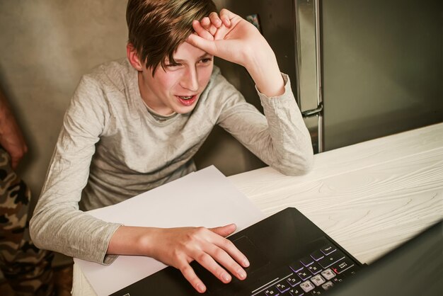 Retrato de un joven usando una computadora portátil en casa