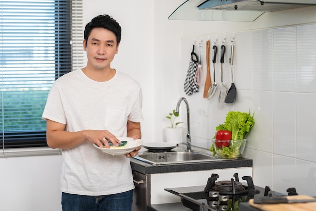 Retrato de un joven usando el teléfono móvil mientras está de pie en la cocina