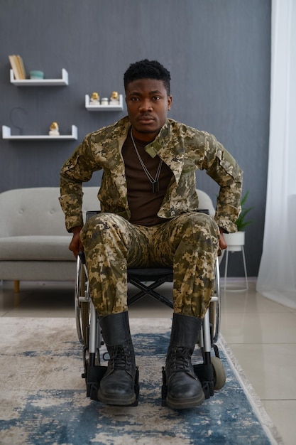 Retrato de joven veterano de guerra triste con discapacidad sentado en silla de ruedas mirando a la cámara