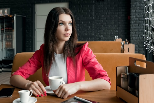 Retrato, jovencita está pasando tiempo en un café para una taza de café. Almuerzo de negocios.