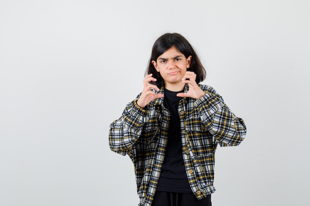 Retrato de jovencita fingiendo sostener algo en camisa casual y mirando molesto vista frontal