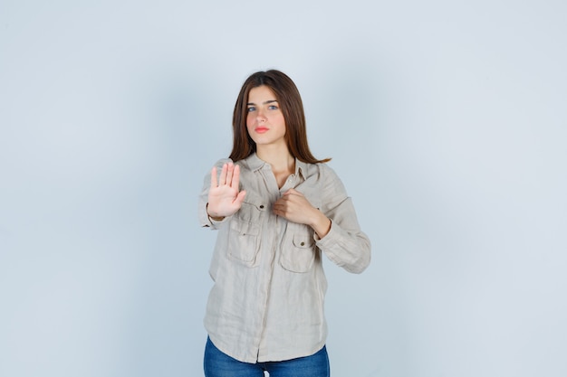 Retrato de jovencita mostrando gesto de rechazo en casual, jeans y mirando confiada vista frontal