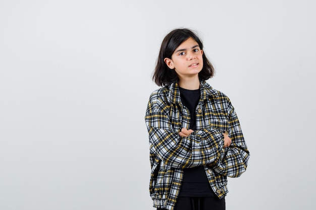 Retrato de jovencita sosteniendo los brazos cruzados mientras posa en camisa casual y mirando enfocado vista frontal