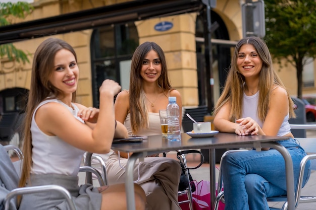 Retrato de jóvenes amigas tomando una copa una tarde en la terraza de una cafetería