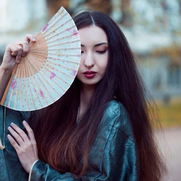 Retrato de jóvenes asiáticos hermosos en kimono gris y con un abanico