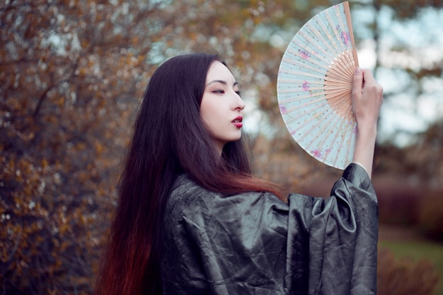 Retrato de jóvenes asiáticos hermosos en kimono gris y con un abanico