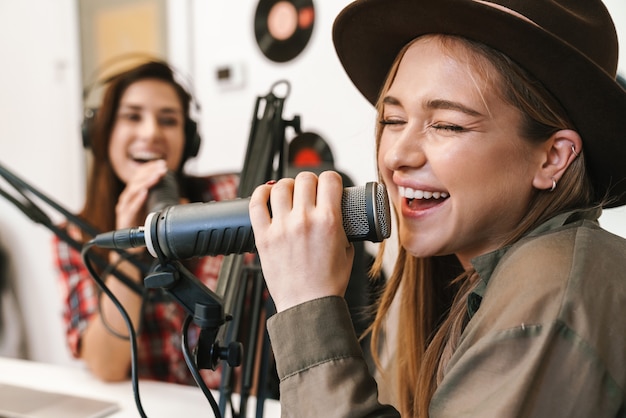 Retrato de jóvenes caucásicos felices actuando en un programa de radio mientras graba un podcast para un programa en línea