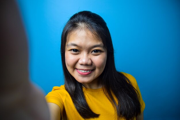 Retrato de jóvenes hermosas mujeres asiáticas con fondo azul aislado tomando selfie