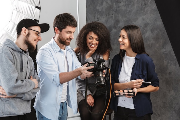 Retrato de jóvenes hombres y mujeres multiétnicos mirando a cámara profesional durante la sesión de fotos en estudio