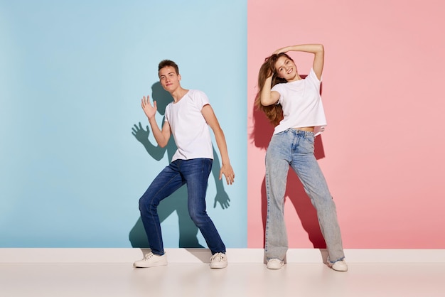 Retrato de jóvenes hombres y mujeres en ropa casual bailando aislado sobre fondo bluepink