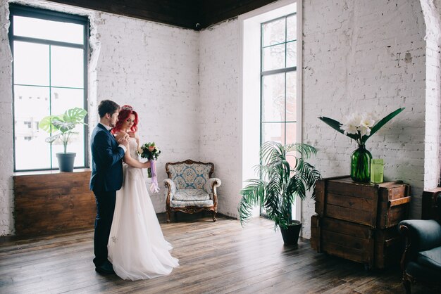 Retrato de jóvenes recién casados felices en una habitación de estilo loft