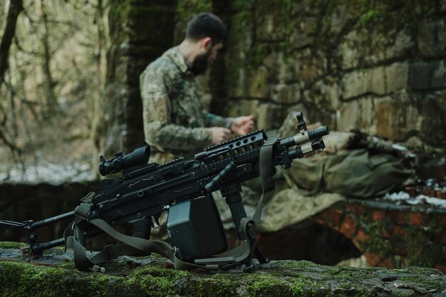 Retrato de jugador de airsoft en equipo profesional con ametralladora en el bosque. Soldado con armas en guerra