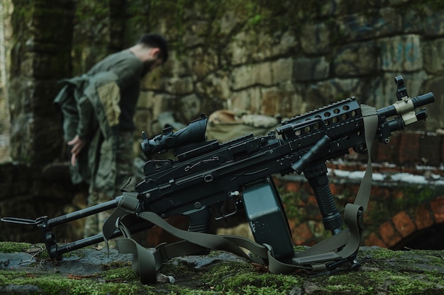 Retrato de jugador de airsoft en equipo profesional con ametralladora en el bosque. Soldado con armas en guerra