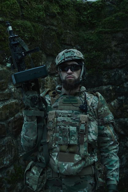 Retrato de jugador de airsoft en equipo profesional con ametralladora en el bosque. Soldado con armas en guerra