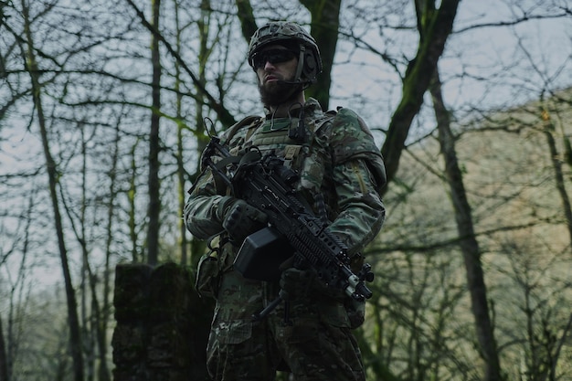 Retrato de jugador de airsoft en equipo profesional con ametralladora en el bosque. Soldado con armas en guerra