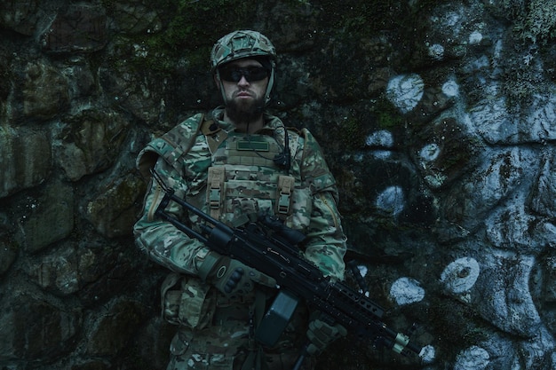 Retrato de jugador de airsoft en equipo profesional con ametralladora en el bosque. Soldado con armas en guerra