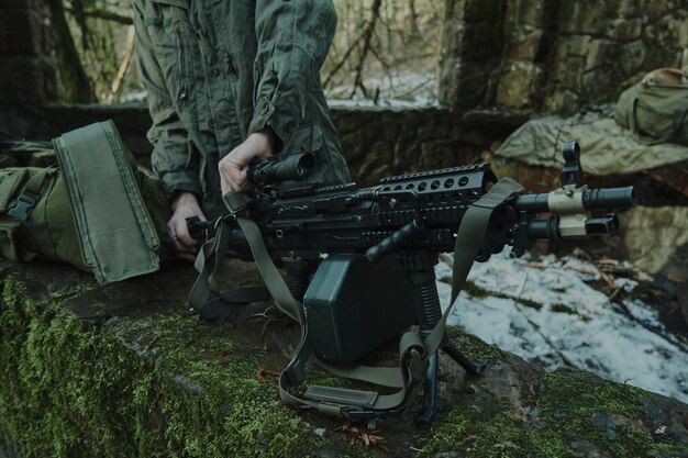 Retrato de jugador de airsoft en equipo profesional carga una pistola con balas en el bosque. Soldado con armas en guerra