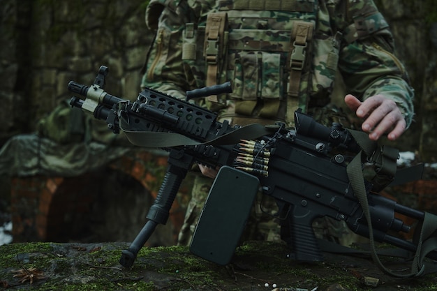 Retrato de jugador de airsoft en equipo profesional carga una pistola con balas en el bosque. Soldado con armas en guerra