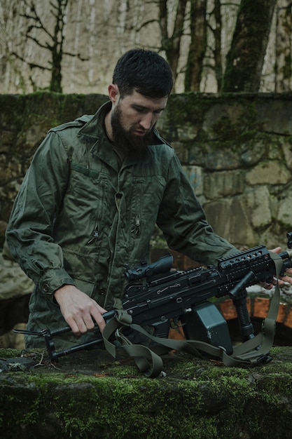 Retrato de jugador de airsoft en equipo profesional carga una pistola con balas en el bosque. Soldado con armas en guerra