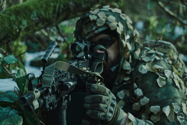 Retrato de jugador de airsoft en equipo profesional en casco apuntando a la víctima con pistola en el bosque. Soldado con armas en guerra