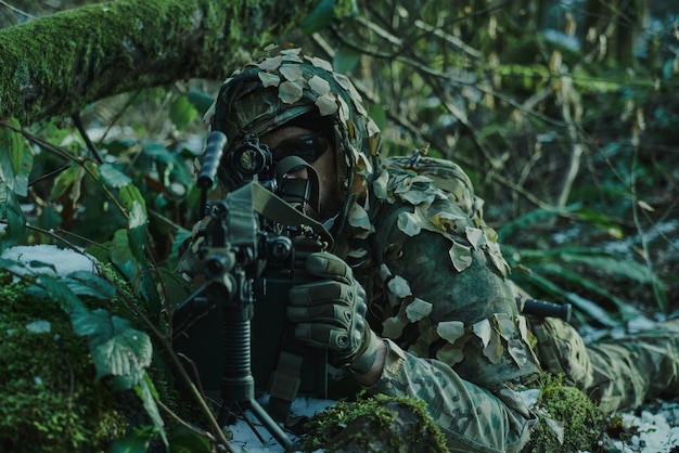 Retrato de jugador de airsoft en equipo profesional en casco apuntando a la víctima con pistola en el bosque. Soldado con armas en guerra