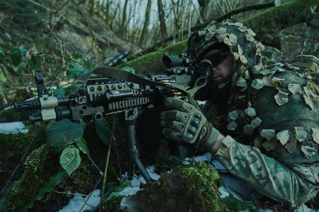 Retrato de jugador de airsoft en equipo profesional en casco apuntando a la víctima con pistola en el bosque. Soldado con armas en guerra