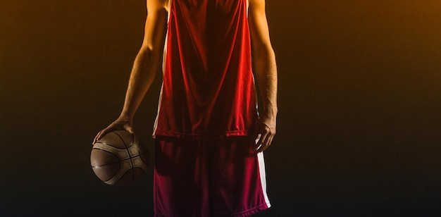 Retrato de jugador de baloncesto sosteniendo una pelota en un gimnasio