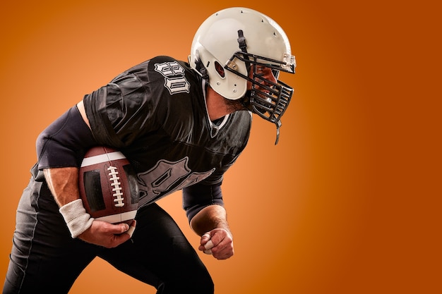 Foto retrato de jugador de fútbol americano con casco de cerca sobre fondo marrón