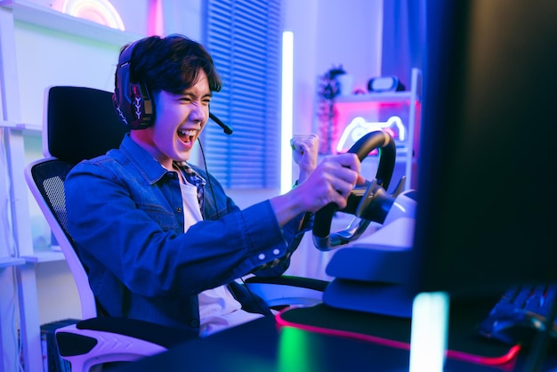 Retrato de un jugador masculino asiático celebrando la victoria frente a la mesa de juego Un jugador que gana un juego de esports con emoción de victoria El jugador se regocija en la victoria en la competencia