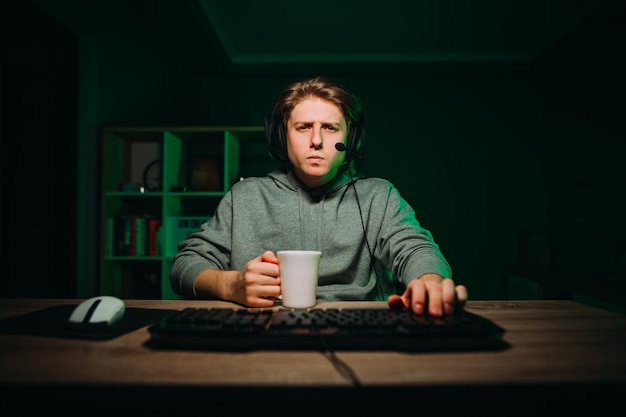El retrato de un jugador pensativo con un auricular en la cabeza usa una computadora con una cara seria