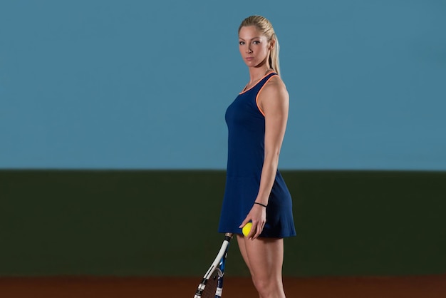 Retrato de jugadora de tenis con raqueta lista para golpear una pelota de tenis