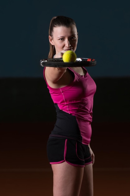 Retrato de jugadora de tenis con raqueta lista para golpear una pelota de tenis