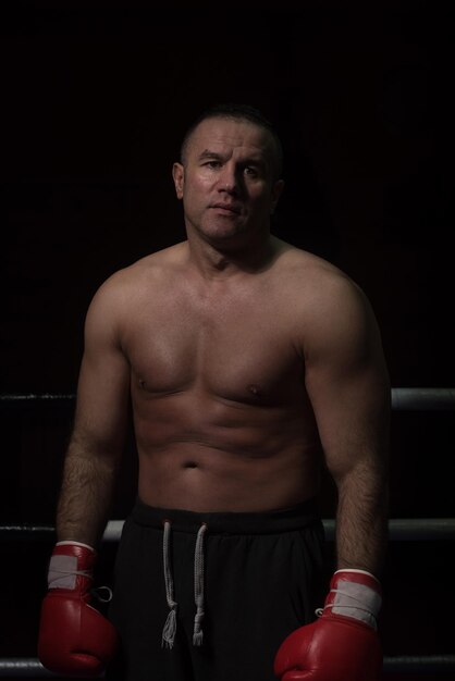 Foto retrato de kickboxer profesional musculoso que está de pie en el ring mientras entrena para la pelea