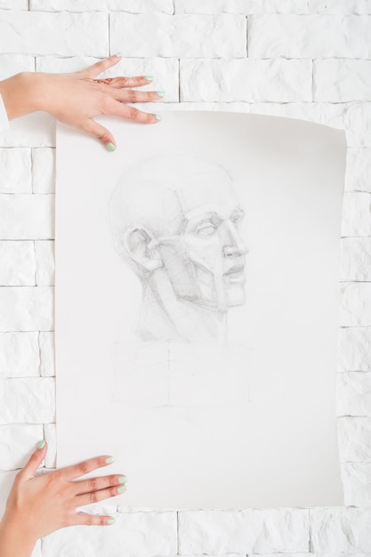 Retrato a lápiz en manos del artista contra la pared