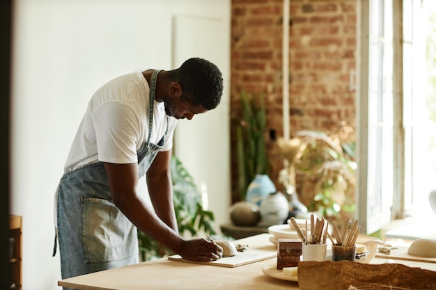 Retrato lateral de um jovem afro-americano criando uma bela tigela artesanal em cerâmica aconchegante