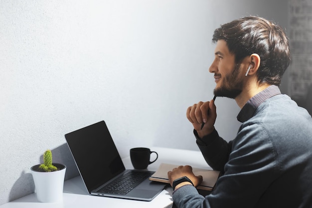 Retrato lateral de um jovem freelancer pensativo trabalhando online em casa