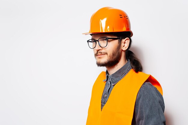 Retrato lateral de ingeniero de construcción en chaleco naranja con casco en blanco