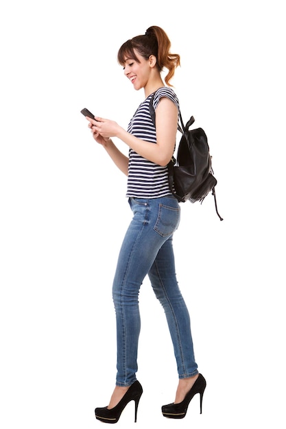 retrato lateral de una mujer joven caminando con teléfono móvil y bolsa contra un fondo blanco