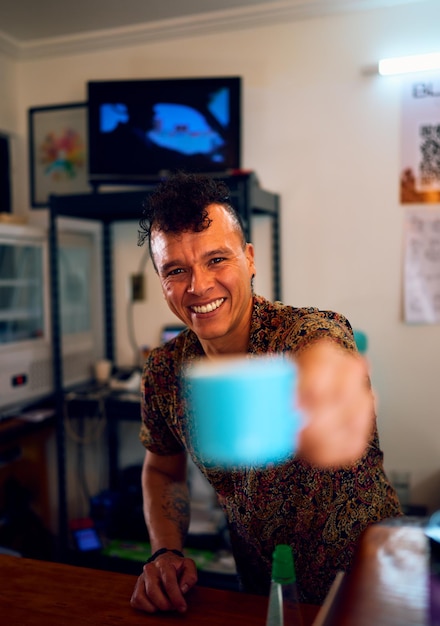 Retrato latino proprietário de uma pequena cafeteria sorrindo e feliz segurando uma xícara de café