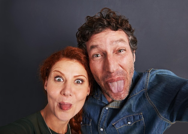 Retrato ligeiramente pateta de um jovem casal feliz fazendo caretas para uma selfie